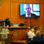 A man appears on a screen in court