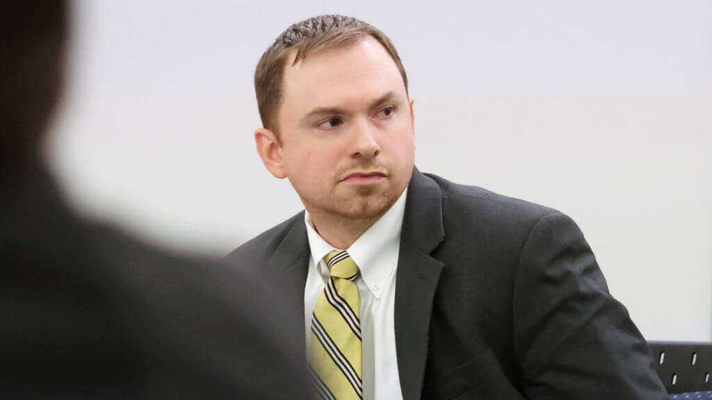 A man in a suit sits in court