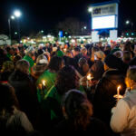 Mass of people holding candles at night at a vigil