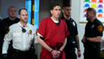 Brian Kohberger, flanked by officers, walks through the courthouse.