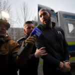 Police officers escort Andrew Tate