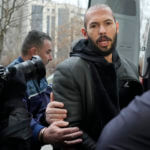 Police officers escort Andrew Tate, handcuffed to his brother Tristan