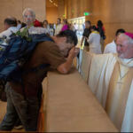 Auxiliary Bishop David O'Connell, right, from the San Gabriel Pastoral Region, is revered by an unidentified pilgrim