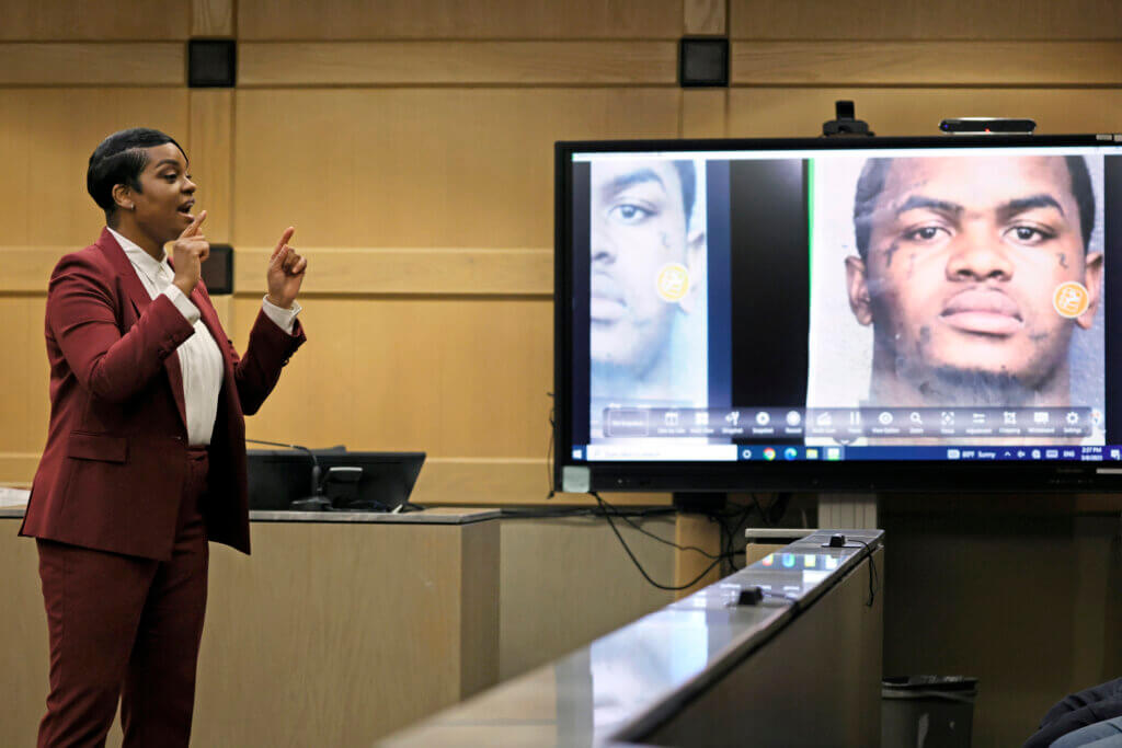Assistant state attorney speaks next to a monitor with a photo in it.