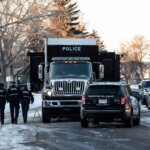 Police investigate the scene where two officers were shot and killed