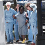 a medical patient in hospital gown is helped by people in scrubs