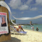 Missing person poster for Natalee Holloway on a pole with beach in background