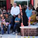 Mass shooting survivor Wilson Garcia, left wearing striped shirt, takes part in a vigil for his son