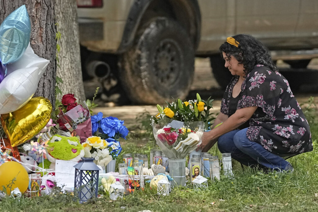 A woman places flowers at a memorial.