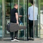 Man walks into revolving doors holding a guitar case