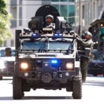 an armored car with officers drives down the street