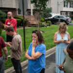 Residents try to take a look as police officers search the house where a suspect has been taken into custody on New York's Long Island