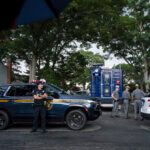 Police officers stand guard near the house where a suspect has been taken into custody on New York's Long Island