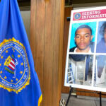 An FBI flag and a seeking information posterboard are set up next to a podium