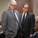 Three men in suits stand in court