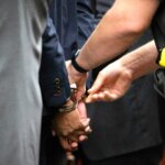 close up showing handcuffs being placed on someone's wrists