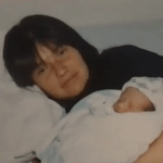 A smiling woman holds a baby