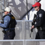 Two police officers walk with long guns