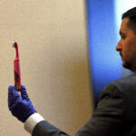 A man holds up a pink child's toothbrush