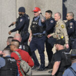 police walk together in vests with guns drawn