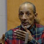 A man gestures with his hands as he testifies.