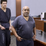Man arrives to courtroom in a prison jumper.