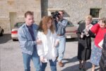 Man holds woman in white being filmed by media