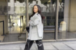 Pretty woman stares down the camera. She has silky long hair and shiny leather pants.