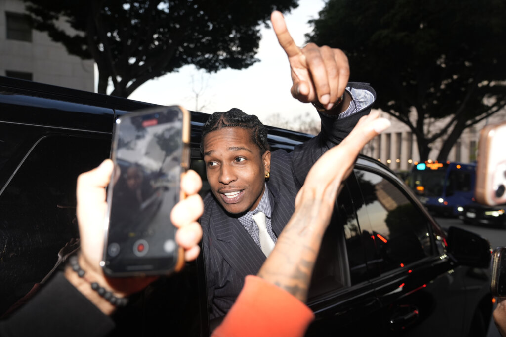 A$AP Rocky gestures out of the window of a vehicle while leaving court