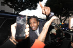 A$AP Rocky gestures out of the window of a vehicle while leaving court