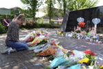 A visitor prays at a memorial to the seven people killed and others injured in the Fourth of July mass shooting at the Highland Park War Memorial