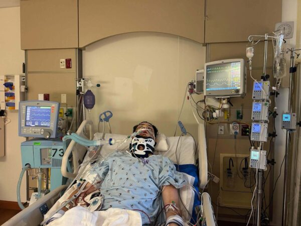 Daniel Waterman lays in a hospital bed with lots of equipment